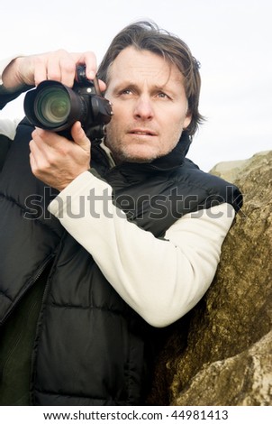 A colour portrait photo of a mature male photographer holding his digital slr camera.