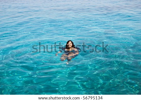 A beautiful indian woman swimming in turquoise blue sea.