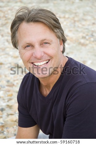 A color portrait photo of a happy smiling man in his forties looking straight at camera.