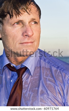 A wet businessman in his forties wearing a blue shirt and red tie.