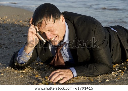 A color portrait photo of a miserable crying businessman on his cellphone and laying on the seashore