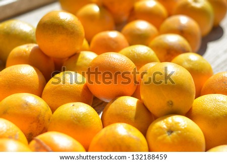 Closeup of a table full of valencia oranges at an outdoor fruit and vegetable stand.