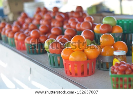 Basket of orange tomatoes for sale at a roadside fruit and vegetable stand.