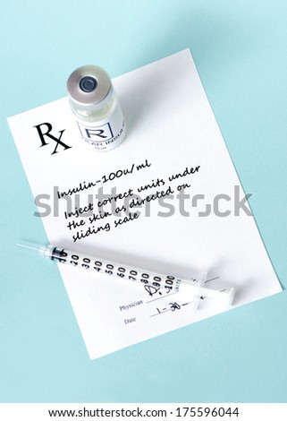 Regular insulin vial with doctor\'s prescription on light blue background.