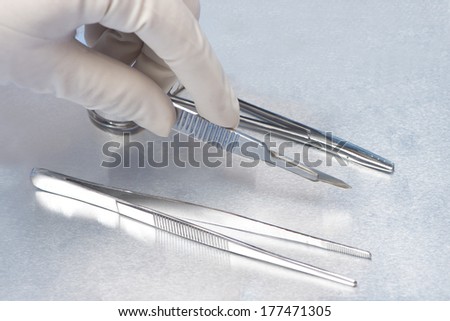 Surgical technician selects a surgical blade from a tray in the operating room.