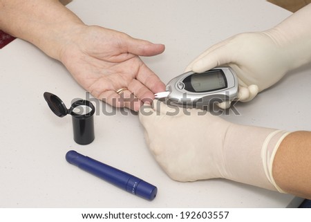 Home health nurse tests patient\'s blood sugar.