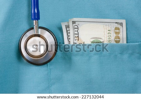 Doctor\'s scrub top with stethoscope and one hundred dollar bill.