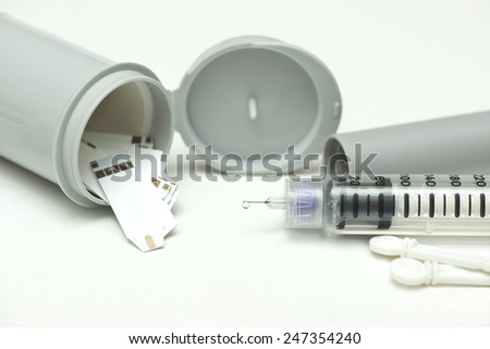 Insulin droplet on insulin pen needle with meter, strip and canister.