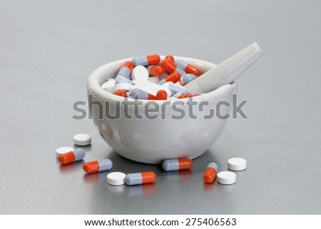 Mortar and pestles with colorful capsules on metal tray.