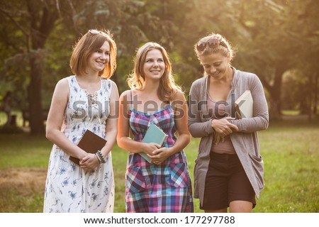 three students discussing books together outdoor