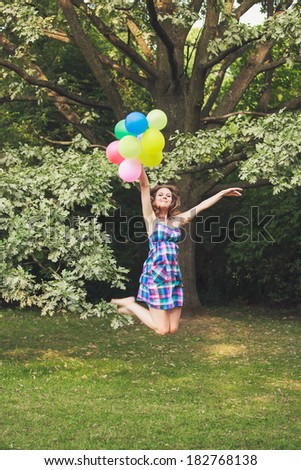 pretty girl playing with balloons in a field on holiday