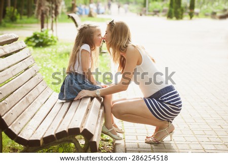 mother kissing daughter in the park