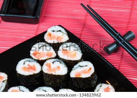 Sushi rolls with salmon and tomato on a black square plate