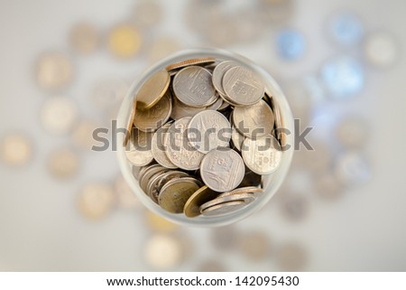 Clear glass jar for tips with money isolated on white. Thailand coins