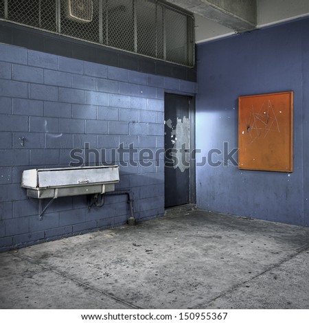 Interior corner of a dilapidated school building with a covered drinking fountain.