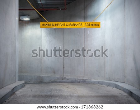 Underground parking garage concrete entrance ramp with height limit sign.