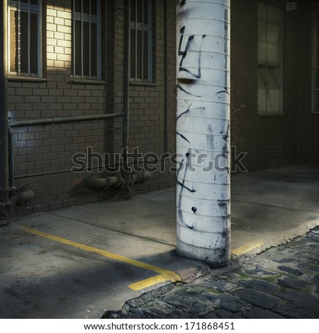Detail of a grungy, round support column beside a warehouse building in subdued light.