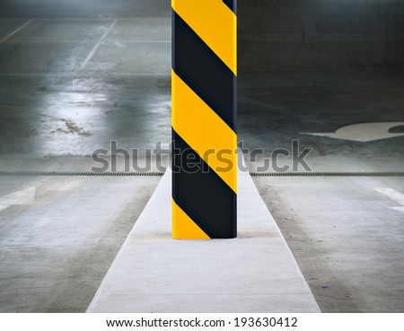 Black and yellow striped column at the entrance to an underground parking garage.