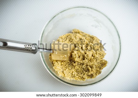 Fresh mixed lemon and poppy seed biscuit dough in glass mixing bowl with spatula, overhead shot.