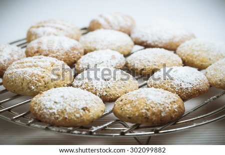Sugar-dusted lemon and poppy seed biscuits, fresh and homemade, resting on a cake rack, with pale seamless background.
