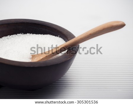 Cooking salt in a wooden bowl with small wooden serving spoon.