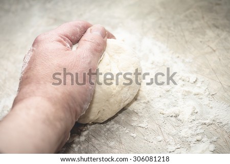 Kneading bread/pizza dough by hand on a scratched kitchen bench top.