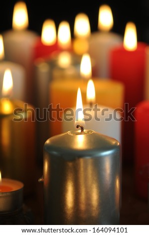 Many lit candles in different colors with beautiful candle flames