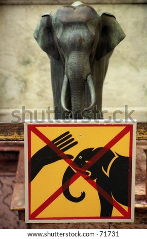 DO NOT touch the elephant sign next to a stone elephant.at the king\'s palace, bangkok, thailand.
