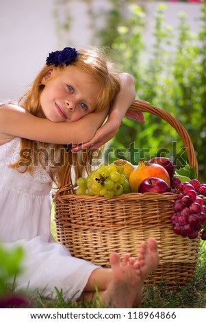 girl sitting on the grass with a basket of fruit