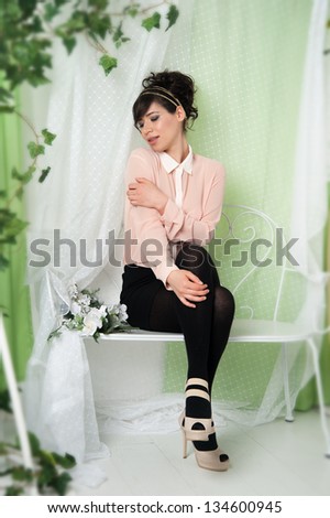 A woman in a pink blouse sitting on a bench in the green.