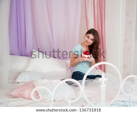 Beautiful woman in bed opening a gift