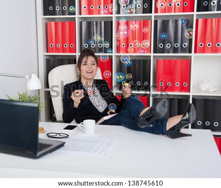 Business woman blowing soap bubbles in a break during working hours