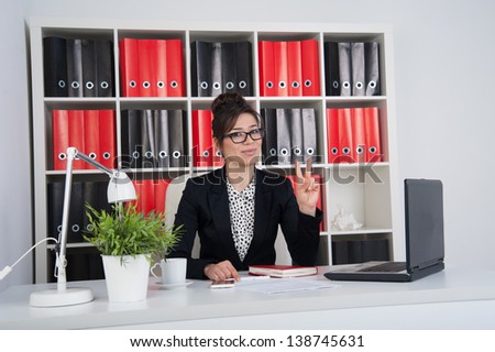 business woman in the office shows sign Victory