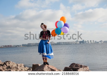 cheerful girl with balloons on the sea in summer