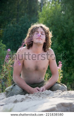 handsome man in the pose of yoga on the sand in the summer
