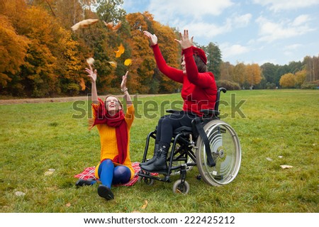 disabled with a friend walking in the autumn Park