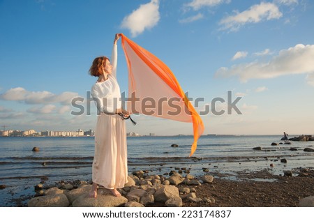 Beautiful young woman holding orange fabric on the wind