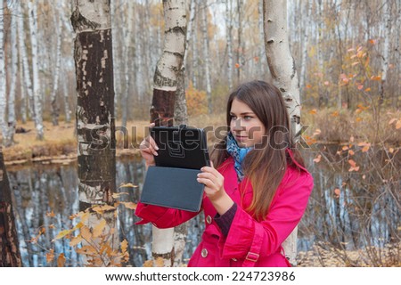 girl in the red coat uses the Internet in the Park