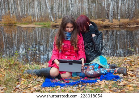 friends using laptop in the autumn park