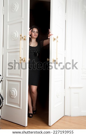 woman in short black dress is at the white door
