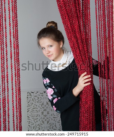 girl looks out from behind the curtain