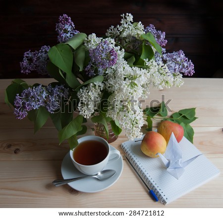 Tea with apples and bouquet of lilac on the table