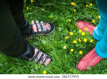 four legs in sneakers standing on the grass