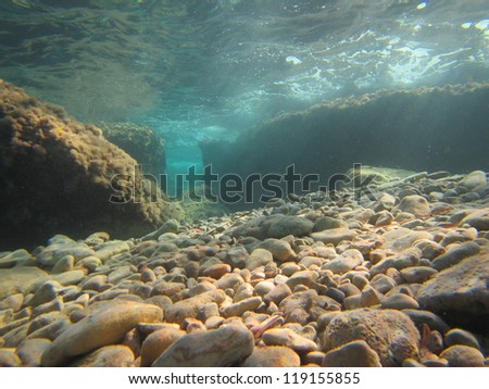 pebble sea bed with an underwater canyon in the background