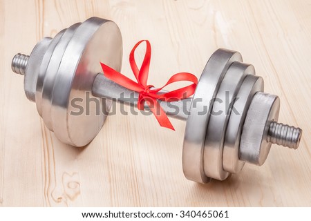 gift - dumbbell tied with red ribbon on wooden desk