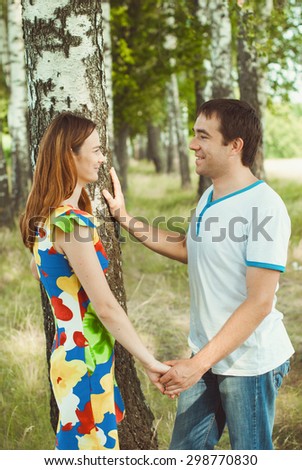 Young happy couple holding hands in the park in the summer.