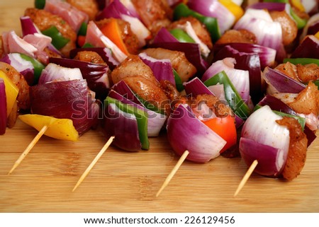 Homemade chicken skewers kebabs with peppers, onions, beacon and herbs marinate on wooden bamboo background