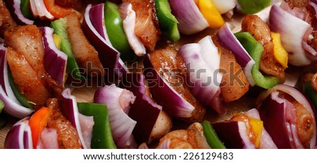 Homemade chicken skewers kebabs with peppers, onions, beacon and herbs marinate on wooden bamboo background
