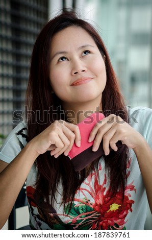 Asian woman holding a pink purse, looking up