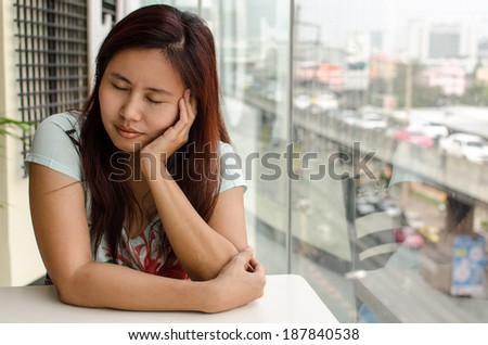 Asian woman closing eyes and putting hand on her chin